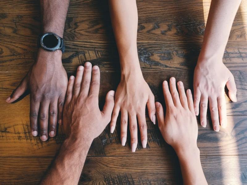 Hands of people with different skin tones resting together